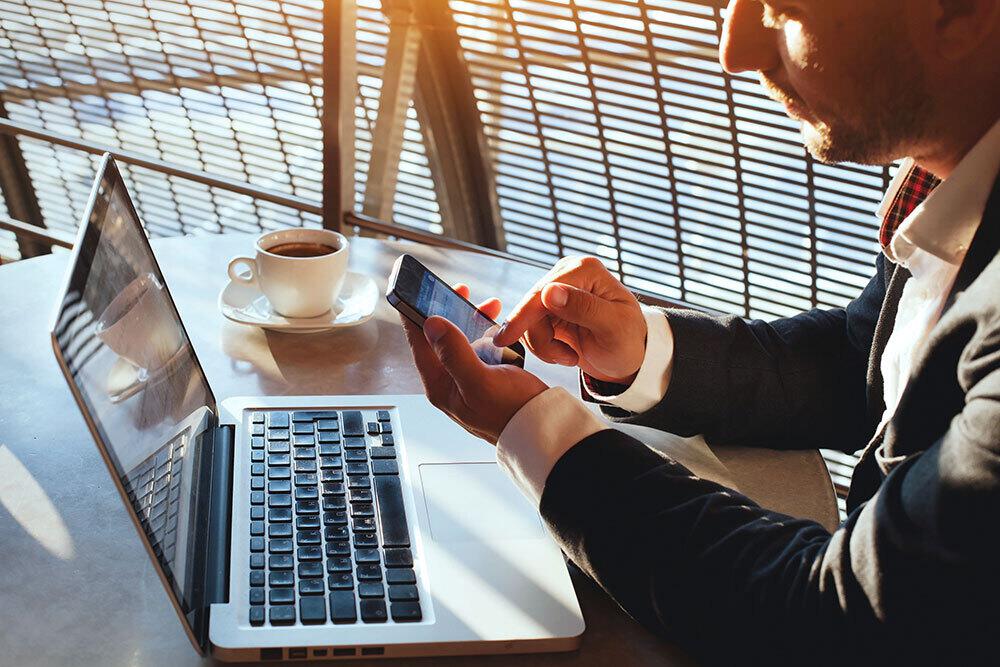 man working on phone and computer